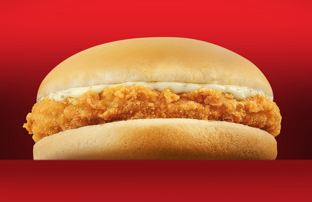 A crunchy fried chicken sandwich stacked with crisp lettuce and creamy sauce